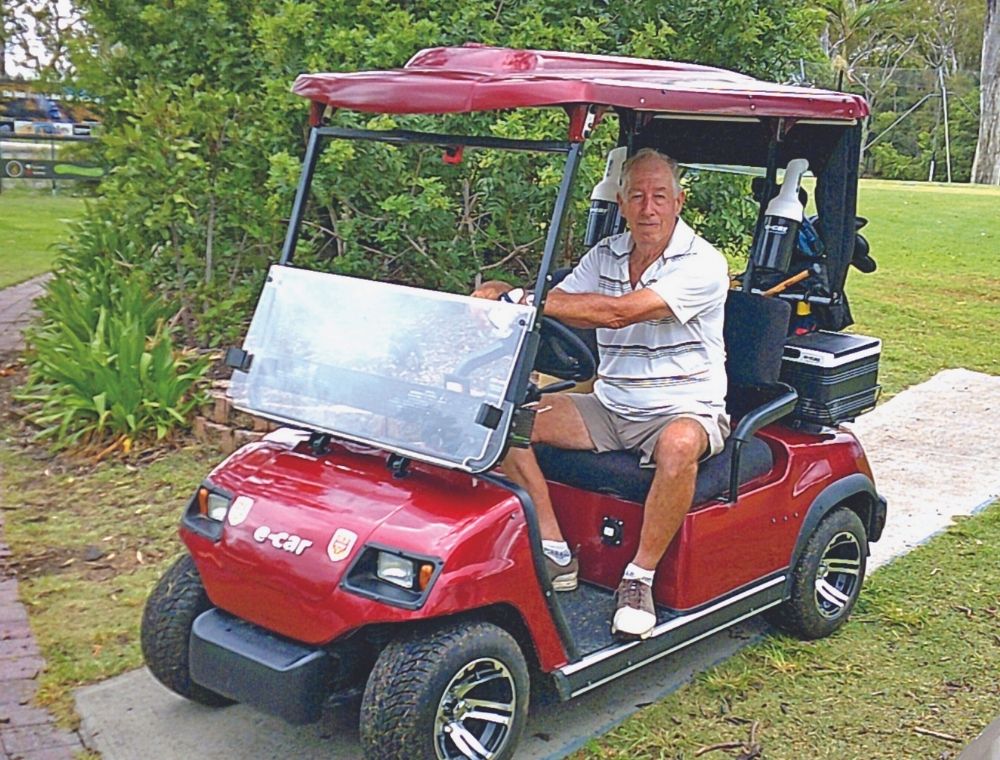 Russell Spencer sitting in red accessible buggy smiling