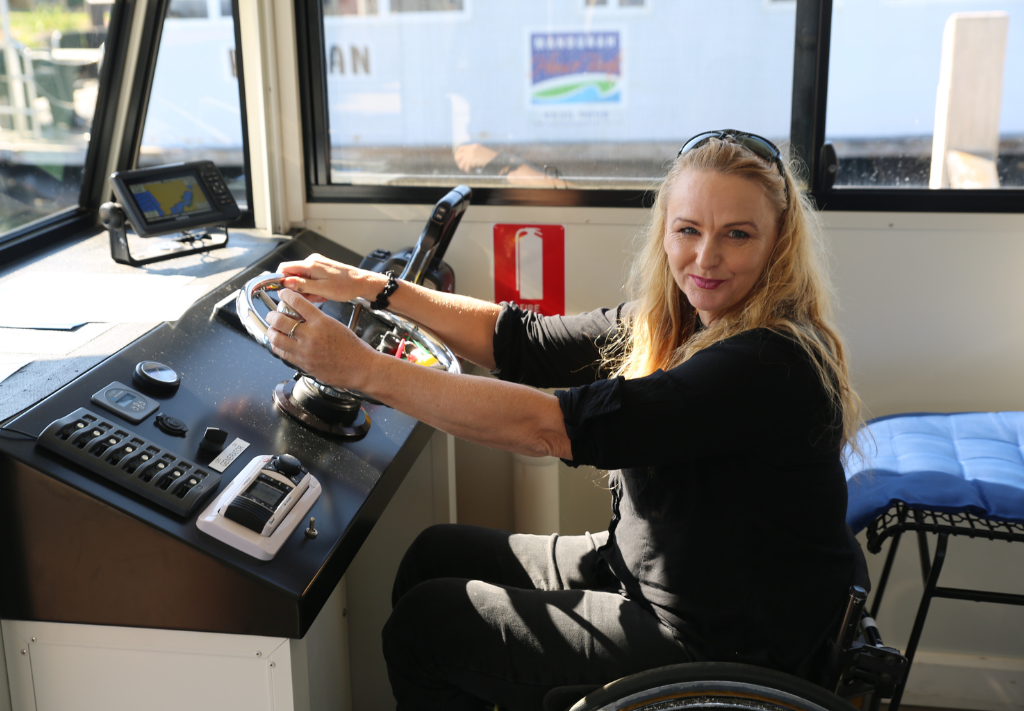 Karen Harvey behind the wheel of an accessible house boat in Mandurah, Western Australia